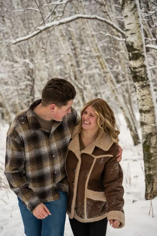 Couple standing close among snowy birch trees